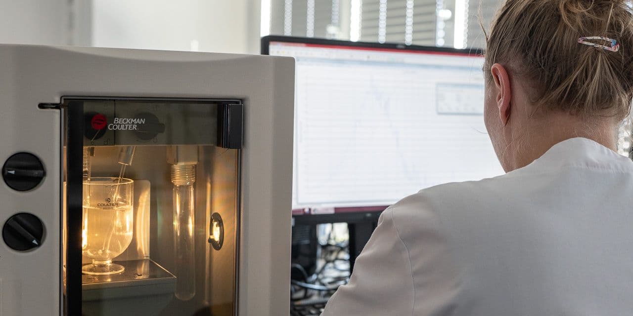 Particle size analyzer with a sample dispersed in liquid, next to a screen showing the size distribution curve.