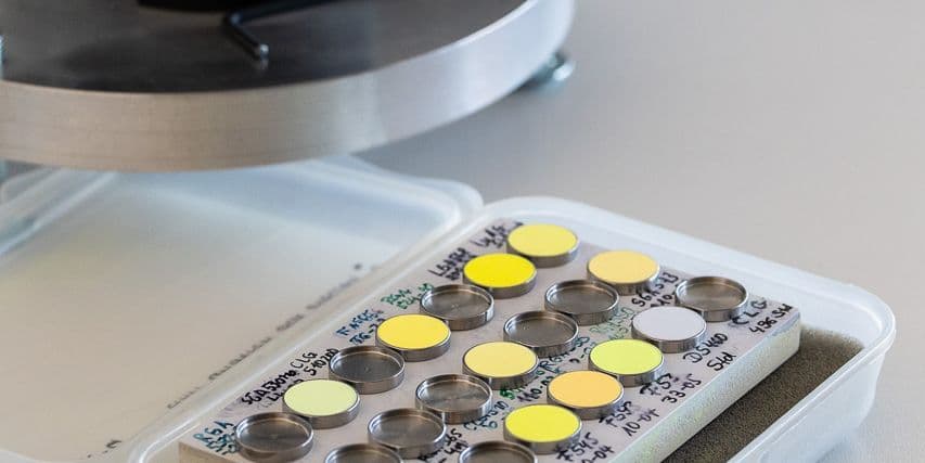 Labelled sample palette with yellow and green phosphor powders in metal pans, next to the integrating sphere.